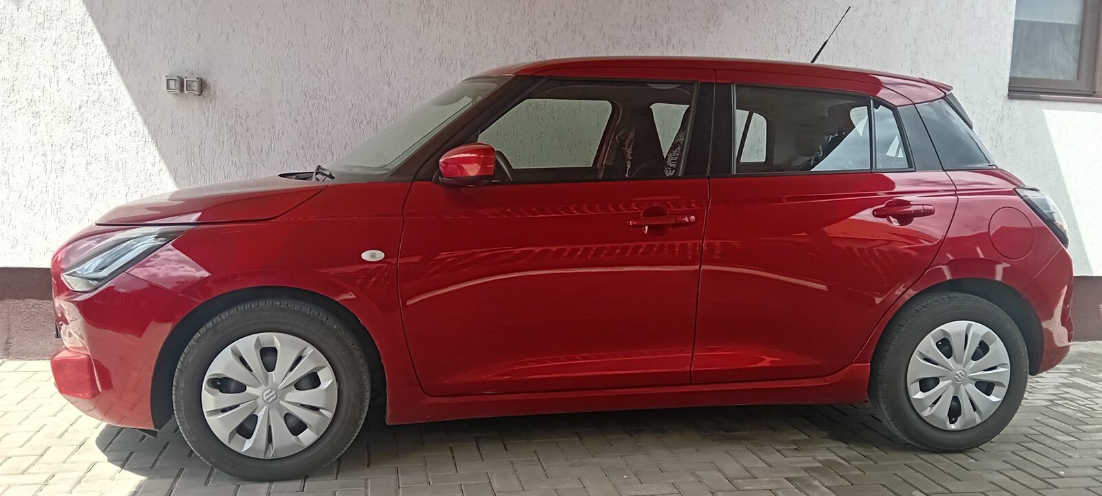 De vanzare Suzuki Swift 1.2 red metalic din 2025, 7000 km, cu 2 seturi de roti (vara si iarna) pe jenti de otel, 15000 euro